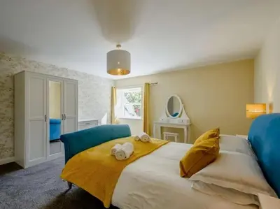 a bedroom with a large bed with a yellow blanket at Nith Riverside Cottages in Sanquhar