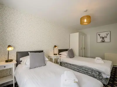 a room with two beds and two tables with lamps at Nith Riverside Cottages in Sanquhar