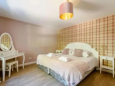 a bedroom with a bed and a desk and a mirror at Nith Riverside Cottages in Sanquhar