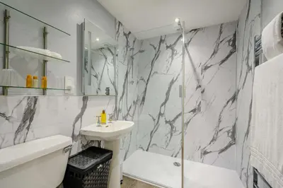 a white bathroom with a sink and a shower at Nith Riverside Cottages in Sanquhar