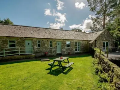a stone house with a picnic table in the yard at Nith Riverside Cottages in Sanquhar