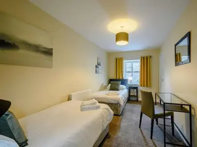 a bedroom with two beds and a desk with a chair at Nith Riverside Cottages in Sanquhar
