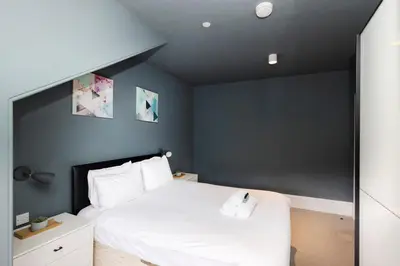 a bedroom with a white bed with a blue wall at JOIVY Spacious Apartment next to West End in Edinburgh