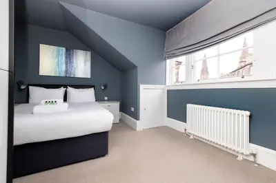 a blue bedroom with a bed and a window at JOIVY Spacious Apartment next to West End in Edinburgh