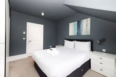 a bedroom with a large white bed and blue walls at JOIVY Spacious Apartment next to West End in Edinburgh