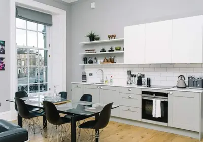 a white kitchen with a dining table and chairs at JOIVY Modern 1 bed flat next to Haymarket Station in Edinburgh