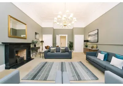 a living room with blue couches and a fireplace at JOIVY Elegant New Town Flat near Princes Street in Edinburgh
