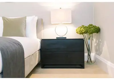 a bedroom with a black dresser with a lamp and flowers at JOIVY Elegant New Town Flat near Princes Street in Edinburgh