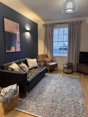 a living room with a black couch and a rug at JOIVY Stylish Castle View Flat with Balcony in Edinburgh