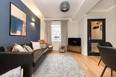 a living room with a black couch and a tv at JOIVY Stylish Castle View Flat with Balcony in Edinburgh