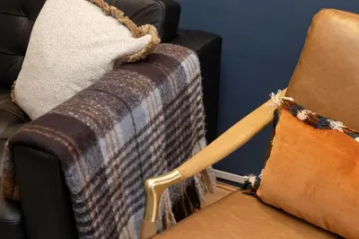 a couch with a blanket and a wooden stick on it at JOIVY Stylish Castle View Flat with Balcony in Edinburgh