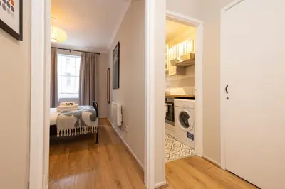 a hallway leading to a kitchen with a washing machine at JOIVY Stylish Castle View Flat with Balcony in Edinburgh