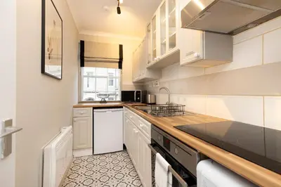 a kitchen with white cabinets and a counter top at JOIVY Stylish Castle View Flat with Balcony in Edinburgh