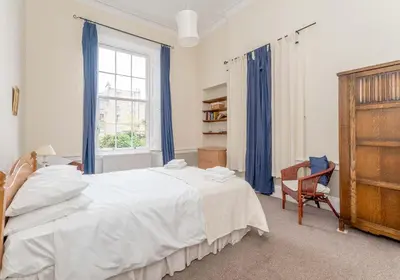 a bedroom with a large white bed and a chair at Melville Street Apartment in Edinburgh