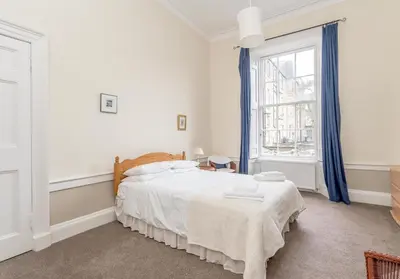 a white bedroom with a bed and a window at Melville Street Apartment in Edinburgh