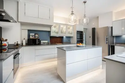 a kitchen with white cabinets and black appliances at Crispie House in Kilfinan
