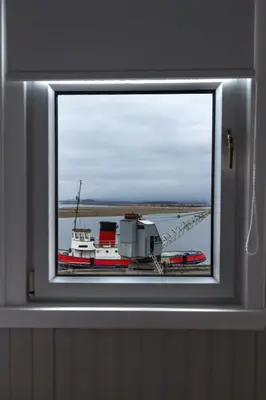 a window in a wall with a boat in the water at Harbourlights Accomodation in Irvine