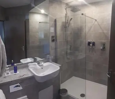 a bathroom with a sink and a shower with a glass door at Seamill House Hotel in Seamill