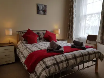 a bedroom with a bed with red pillows on it at Charlotte Street 2 Bedroom Apartment in Ayr