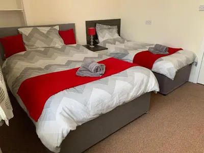 two beds in a bedroom with red and white at Charlotte Street 2 Bedroom Apartment in Ayr