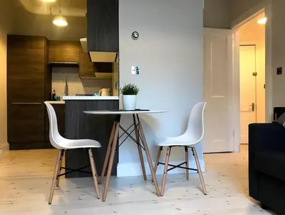 a kitchen with a table and two white chairs at Relax In Style In Edinburghs Buzzing West End in Edinburgh
