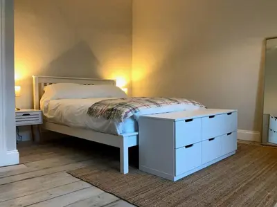 a bedroom with a white bed and a dresser at Relax In Style In Edinburghs Buzzing West End in Edinburgh