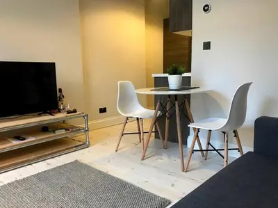 a living room with a table and chairs and a tv at Relax In Style In Edinburghs Buzzing West End in Edinburgh
