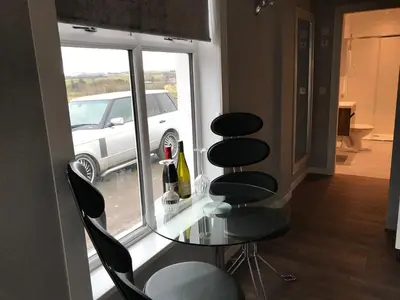 a glass table and chairs in front of a window at Carriage Cottage Hot Tub in Beith