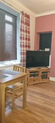 a living room with a flat screen tv and a table at Millhill St Dunfermline in Dunfermline