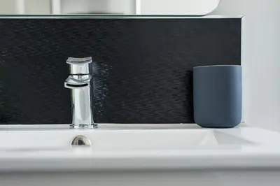 a bathroom sink with a faucet and a cup at The Roseburn Apartment in Edinburgh