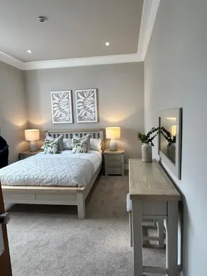 a bedroom with a bed and a table and a mirror at Crookston Hotel in Glasgow