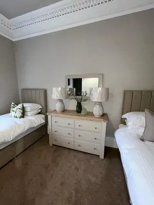 a bedroom with two beds and a dresser with a mirror at Crookston Hotel in Glasgow
