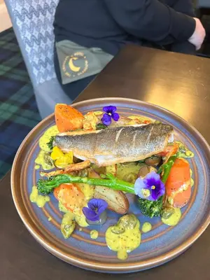 a plate of food with a fish and vegetables at Crookston Hotel in Glasgow