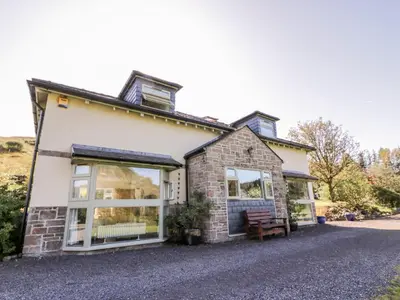 an old stone house with large windows on a driveway at Glen Euchar House in Kilninver