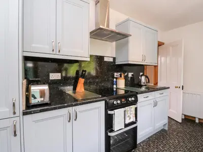a kitchen with white cabinets and a black stove top oven at Forester's Cottage in Newyork