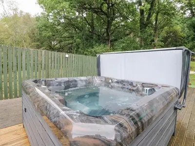 a jacuzzi tub on a deck with a fence at Heatherbank in Garelochhead
