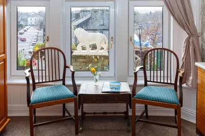 two chairs and a table with a white horse statue in a window at Castle Walk Bed & Breakfast in Stirling