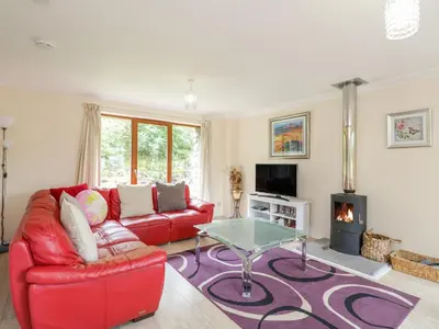 a living room with a red couch and a glass table at Woodland Villa in Oban