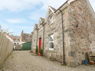 an old stone house with a red door at The Knowe Upper in Taynuilt