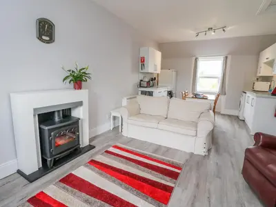 a living room with a white couch and a fireplace at The Knowe Upper in Taynuilt
