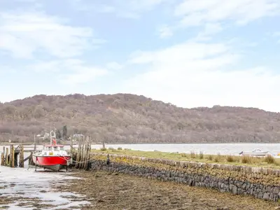 a boat is docked on a beach next to the water at The Knowe Lower in Taynuilt