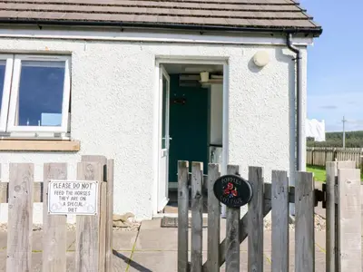 a house with a fence with a sign in front of it at Poppies Cottage in Craignure