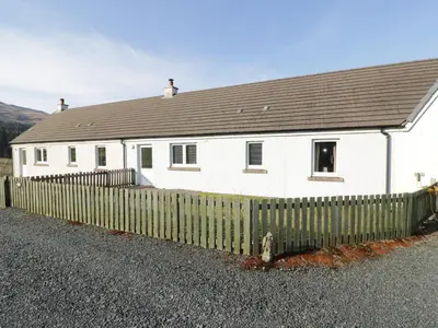 a white house with a fence in front of it at Poppies Cottage in Craignure