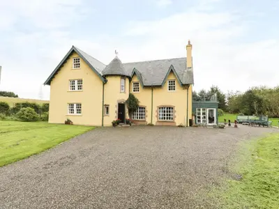 a large yellow house with a gravel driveway at Tulchan Lodge in Buchanty