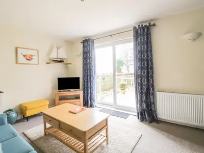 a living room with a blue couch and a window at Pebble Nook in Onich