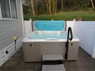 a hot tub with a chair in a backyard at Woodstock Lodge in Skelmorlie