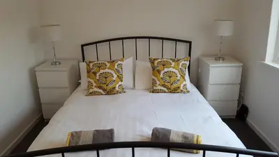 a bedroom with a white bed with two night stands at Flemming Place in East Kilbride