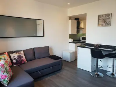 a living room with a couch and a kitchen at Stylish City Apartment - Near Haymarket, Walk to Castle and Princes Street in Edinburgh