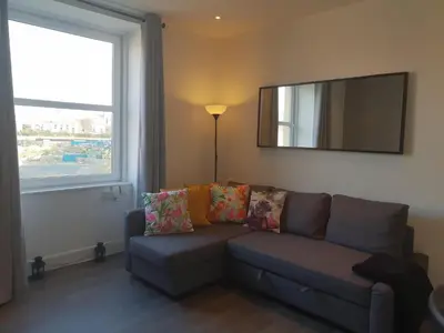 a living room with a couch and a mirror at Stylish City Apartment - Near Haymarket, Walk to Castle and Princes Street in Edinburgh