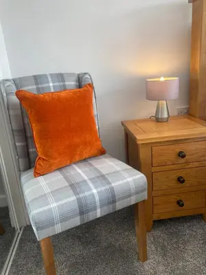 an orange pillow sitting on a chair next to a nightstand at Central West End City Apartment in Glasgow